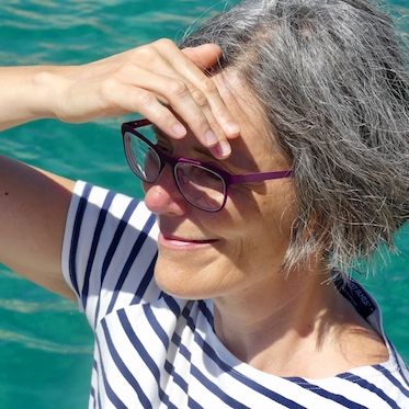 Karin Graf mit Blick auf das Meer mit der rechten Hand als Sonnenschutz